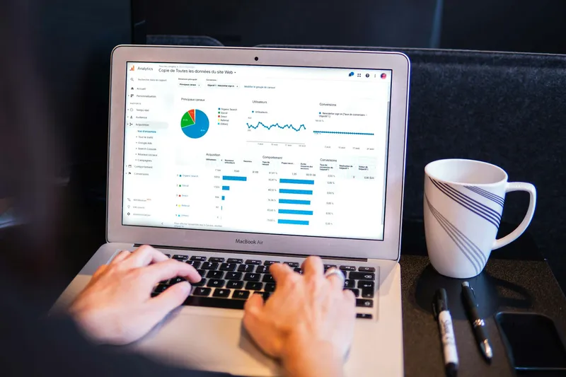 A flat lay of a person holding a smartphone showing analytics, with a laptop and coffee